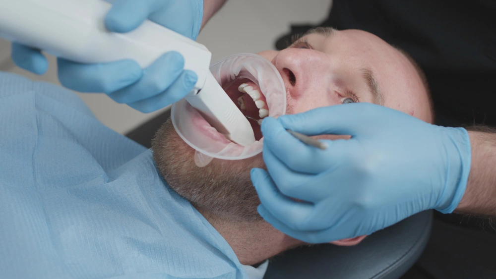 Doctor scans the teeth of a male patient in the medical office of clinic.