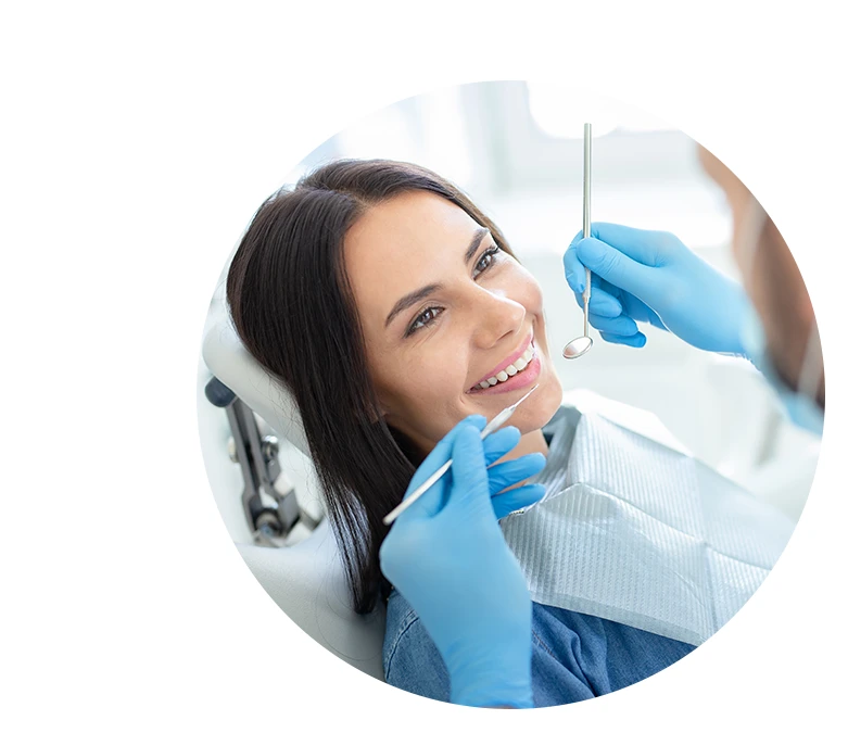 smiling happy client in dental chair with doctor looking her with instruments